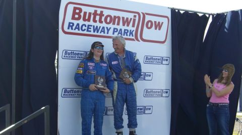 1990 Ford Probe - Two individuals in racing attire stand on a podium with the Buttonwillow Raceway Park logo behind them.