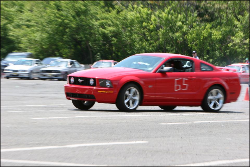 Red Ford Mustang with number 65 on the door, seen from the front-three-quarter angle during an autocross event