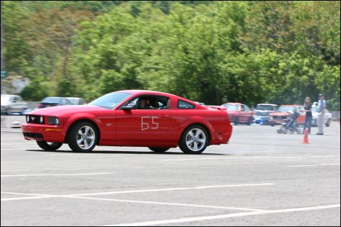 2001 Mercury Grand Marquis - A red Ford Mustang GT with the number 65 is seen in motion during an event, with other vehicles and spectators present.