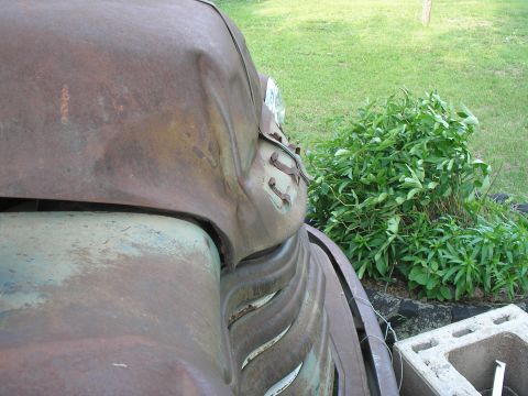 1951 Chevrolet C/K Pickup - Close-up of a heavily rusted 1951 Chevrolet C/K Pickup's front fender and headlight assembly, showing significant wear and damage.