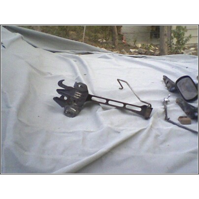 1973 Ford Ranchero - A disassembled car part rests on a tarp outdoors, with trees and a building in the background.