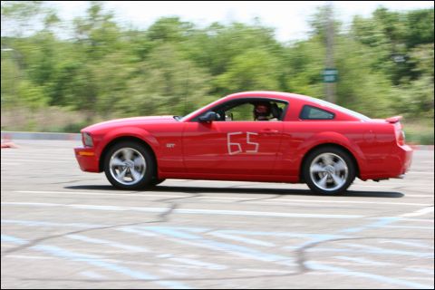 2001 Mercury Grand Marquis - A red Ford Mustang is seen in profile on a race track, with the number 65 visible on its side.