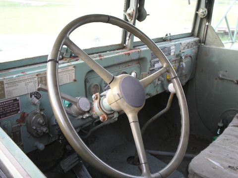 1951 Chevrolet C/K Pickup - The interior of a utilitarian vehicle shows a worn steering wheel and a dashboard covered in various warning labels.