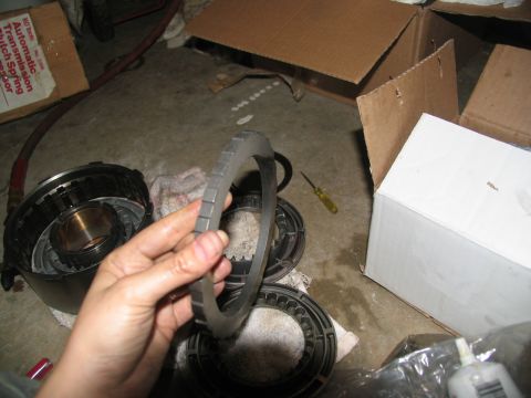1978 Ford Bronco - Disassembled automatic transmission components are laid out on a concrete floor with a hand holding a ring gear.