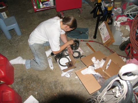 1978 Ford Bronco - A person is kneeling on the floor, assembling transmission components from various boxes and containers.