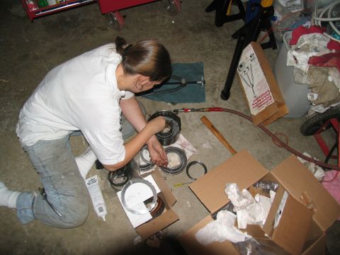 1978 Ford Bronco - Mechanic disassembles transmission clutch pack components in a garage setting.