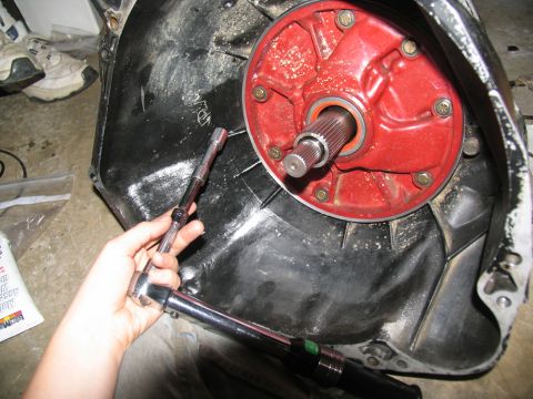 1978 Ford Bronco - A person uses a torque wrench and ratchet on a transmission bell housing with a red input shaft housing.