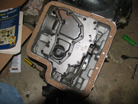 1978 Ford Bronco - Replacing the transmission pan gasket on a Ford vehicle. A Haynes manual is nearby.