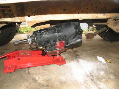 1978 Ford Bronco - Transmission removed from vehicle and supported by a red jack.