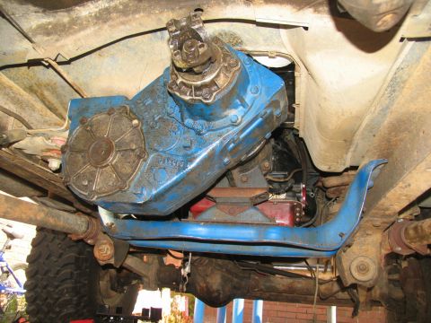 1978 Ford Bronco - Underside view of a vehicle's drivetrain, focusing on a blue transfer case and associated parts.