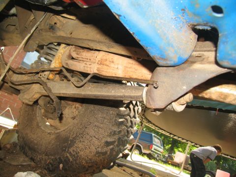 1978 Ford Bronco - Undercarriage detail with a tire and exhaust system; another vehicle is in the background.