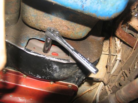 1978 Ford Bronco - A ratchet is used on a bolt near the transmission components of a vehicle.