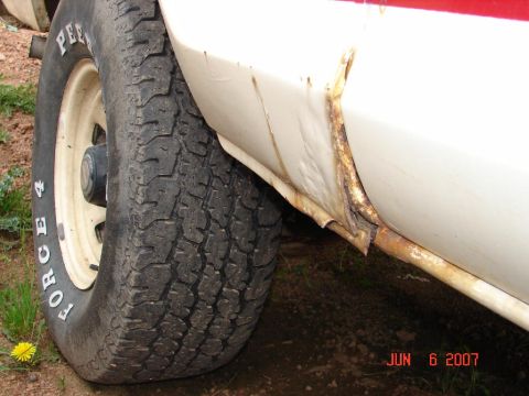1978 Ford Bronco - Significant rust is visible on the lower body panel of this white vehicle, next to a tire with 'PEERLESS FORCE 4' lettering.