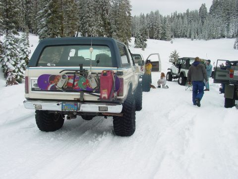 1986 Ford Bronco - A group of vehicles and people are gathered in a snowy, wooded area, with one Bronco loaded for a winter outing.