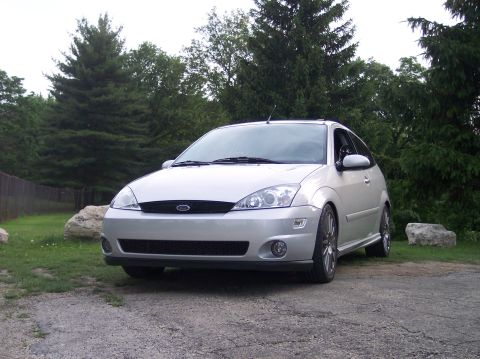 2003 Ford Focus - A silver 2003 Ford Focus hatchback is parked outdoors on a gravel driveway.