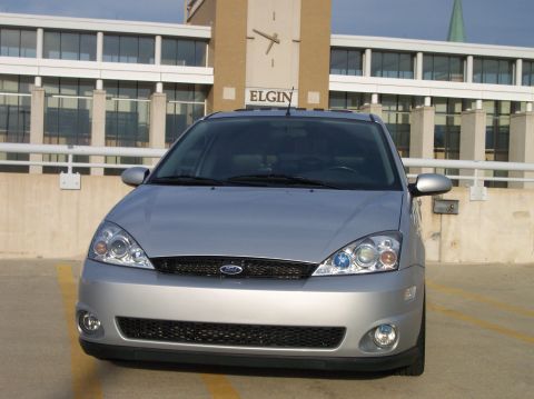 2003 Ford Focus - Front view of a silver Ford Focus hatchback parked in a lot, with a building and clock tower in the background.