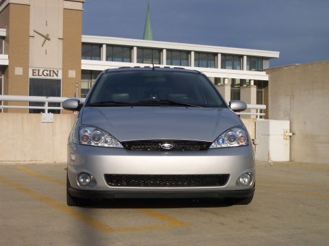 2003 Ford Focus - Front view of a silver 2003 Ford Focus parked in a lot with a building a large clock in the background.