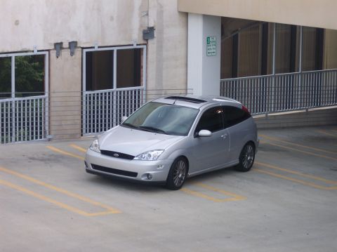 2003 Ford Focus - Silver 2003 Ford Focus hatchback parked in a lot with yellow lines.