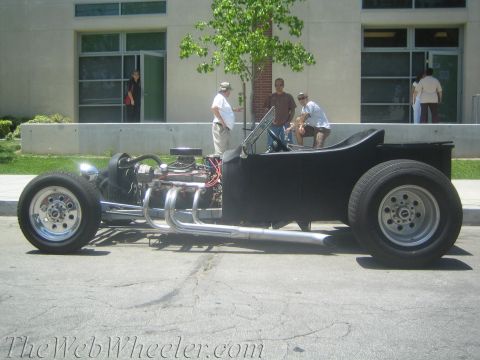 1968 Ford Mustang - Side view of a custom hot rod with exposed engine and large rear tires parked on asphalt.