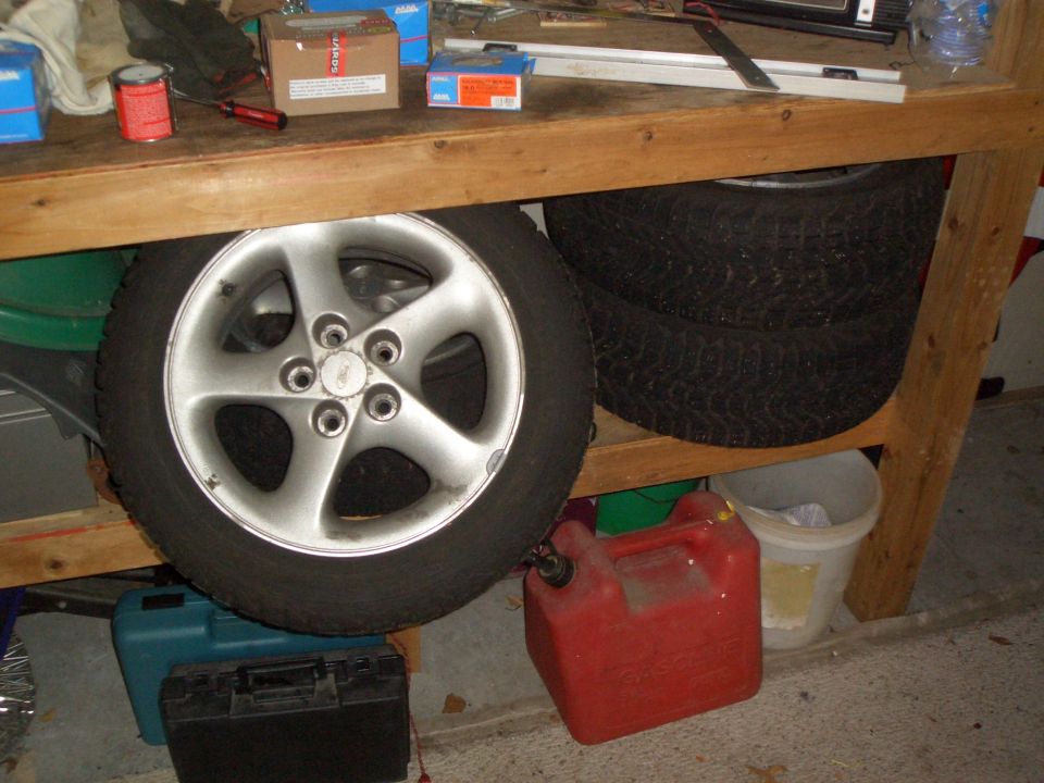 Alloy wheel and tire stored under a garage workbench