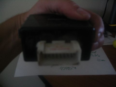 1994 Ford Bronco - A hand holds a black electronic module with a white connector attached.
