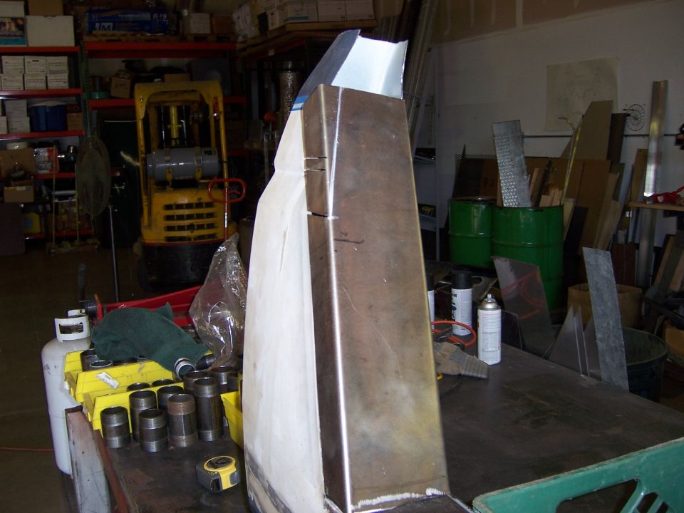 Metal pieces being worked on in a workshop, with a forklift in the background