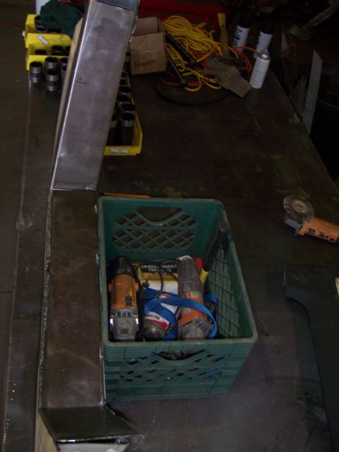 1991 Ford Bronco - A green plastic crate holds several angle grinders and other tools on a cluttered workbench.