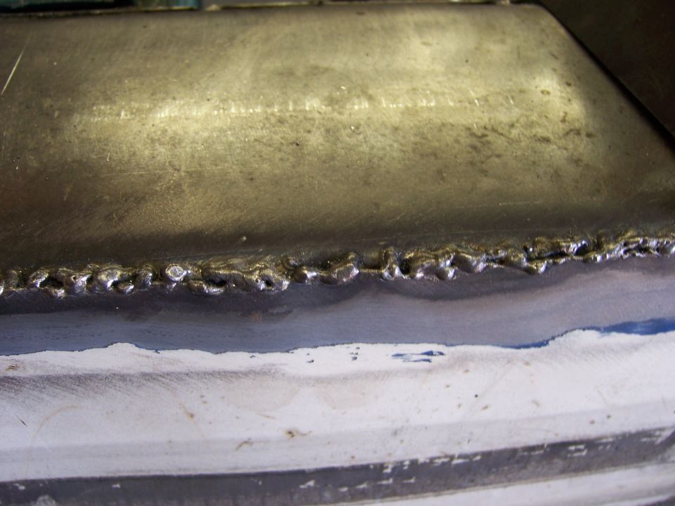 Close-up of a rough, welded metal seam on a white surface