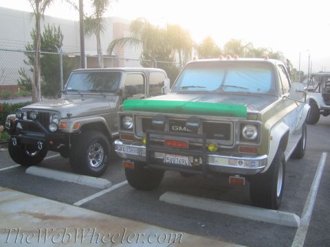1987 Suzuki Samurai - Two off-road vehicles are parked in a lot, one is a Jeep and the other is a GMC truck.