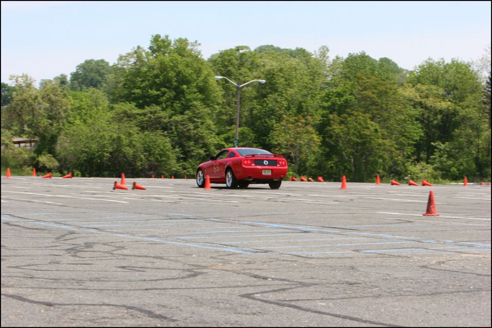 Red sports car on asphalt course with orange cones. Rear view
