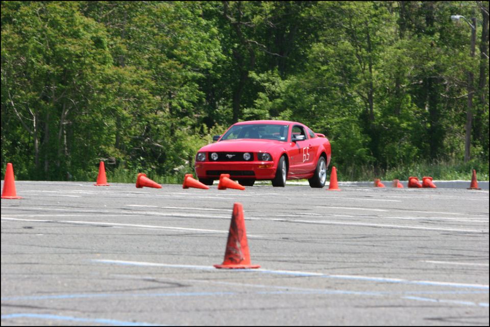Red Ford Mustang with number 65 on the side, navigating an autocross course with orange cones