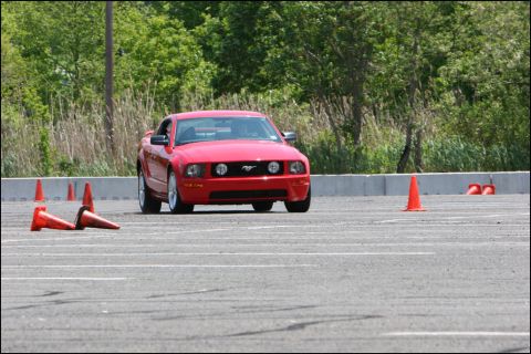 2001 Mercury Grand Marquis - Red Ford Mustang navigates an autocross course marked by orange cones.