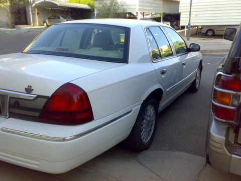 2007 Mercury Grand Marquis - A white sedan is parked next to a silver SUV. The sedan appears to be a Ford Crown Victoria or Mercury Grand Marquis.
