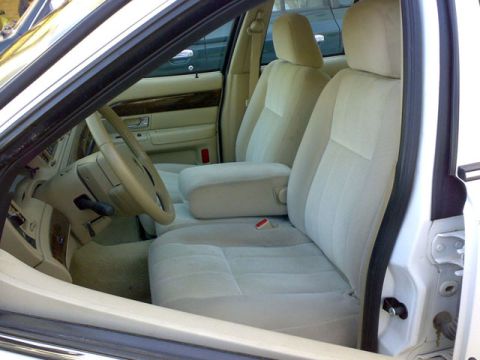 2007 Mercury Grand Marquis - The interior of a 2007 Mercury Grand Marquis features tan cloth seats, a center console armrest, and wood grain accents on the door panels.