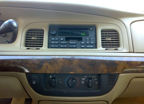 2007 Mercury Grand Marquis - The dashboard features a digital clock on the radio and wood grain trim around the climate controls.