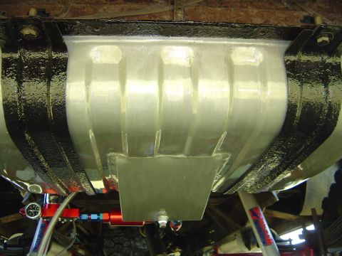 1978 Ford Bronco - The underside of a vehicle reveals a substantial fuel tank, complete with auxiliary plumbing and a pressure gauge.