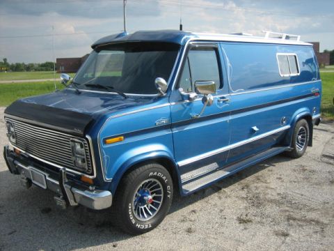 1978 Ford E250 - This blue van features a prominent chrome grille, side steps, and custom pinstriping, consistent with a 1978 Ford E250 model.