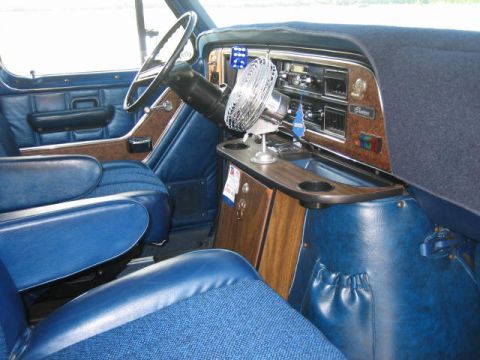 1978 Ford E250 - The dashboard and front seats of a van are shown, blue upholstery and wood-grain accents.