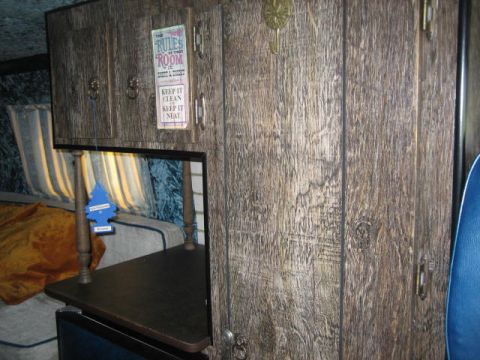 1978 Ford E250 - Interior view of a van wood paneling, a bed, and a decorative sign with rules for the room.