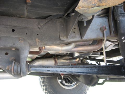 1979 Ford Bronco - The underside of a vehicle is shown, revealing its exhaust system and suspension components.