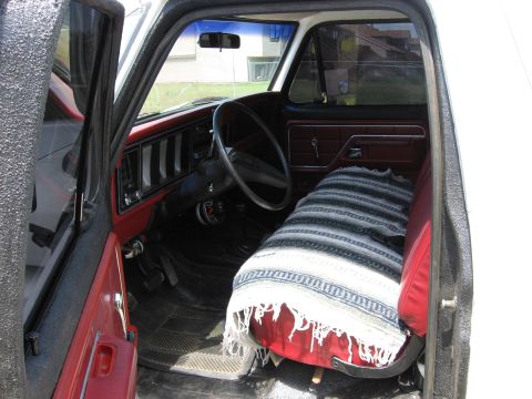 1979 Ford Bronco - The interior of a truck shows a bench seat covered with a blanket and a dashboard with vertical vents.