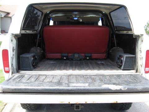 1979 Ford Bronco - Rear view of a white 1978 Ford Bronco showing the cargo area with a red bench seat and two speakers.