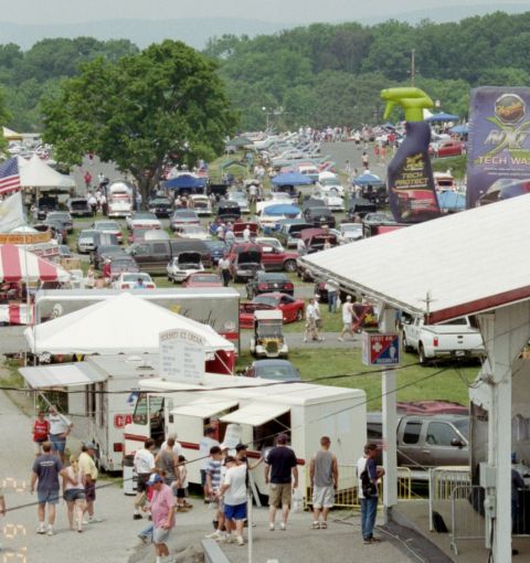 1976 Ford Ranchero - A busy outdoor event features numerous cars, tents, and attendees enjoying the day.
