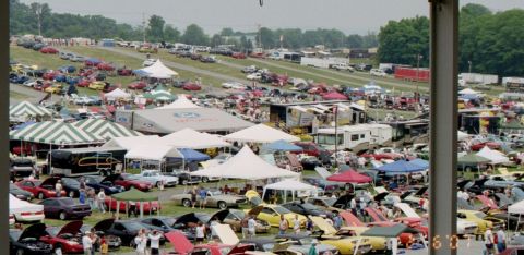 1976 Ford Ranchero - A wide view of a car show with numerous vehicles and tents spread across a grassy field.