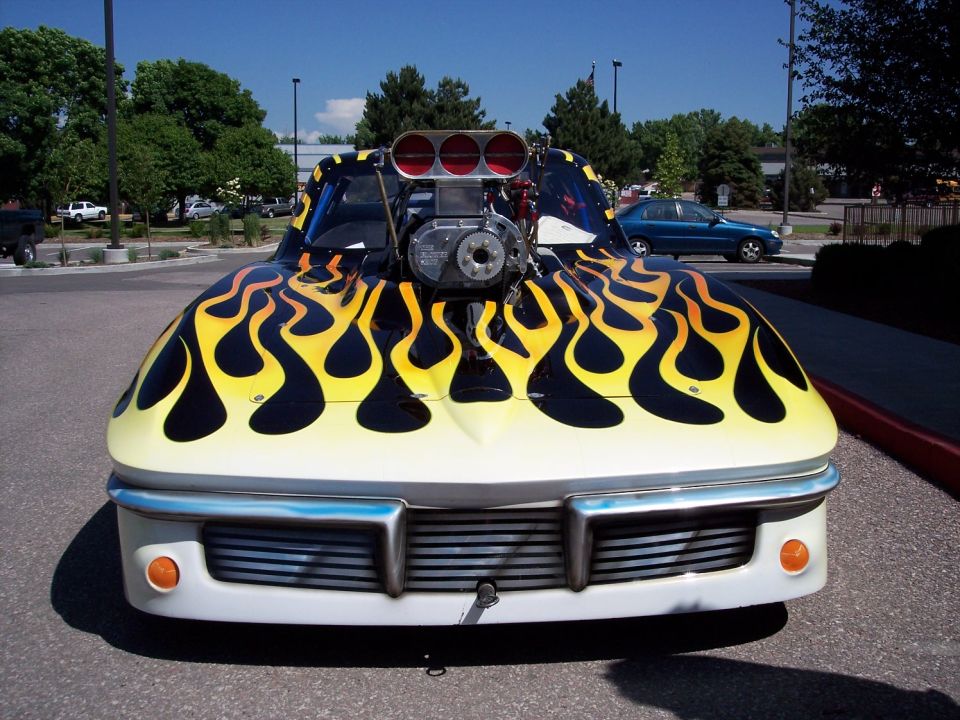 Front view of a custom hot rod with yellow and black flames and a prominent engine blower