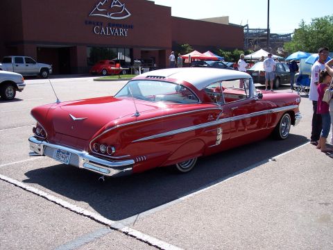 1972 Ford Ranchero - A classic red car with a white roof is parked outside a building with a sign that reads 'Rocky Mountain Calvary'.
