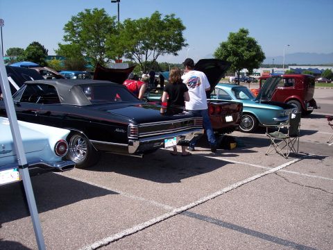 1972 Ford Ranchero - A black convertible with red trim is parked next to other vehicles at an outdoor event.