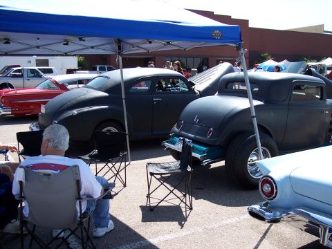 1972 Ford Ranchero - A dark hot rod coupe is parked under a blue canopy at an outdoor event.