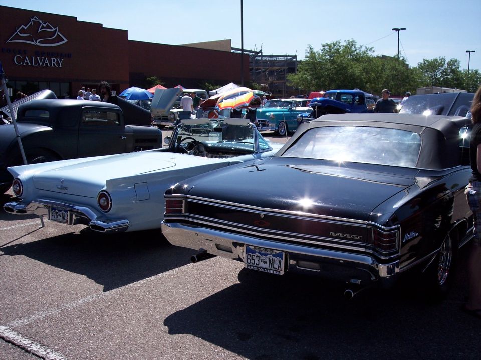Black 1967 Chevrolet Chevelle convertible parked next to a light blue 1957 Ford Thunderbird convertible