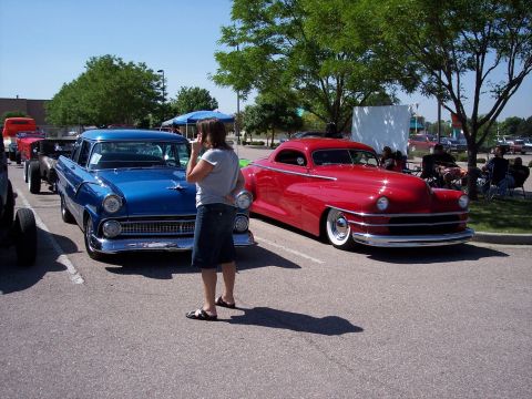 1972 Ford Ranchero - Two vintage vehicles are displayed at an outdoor event, with a woman standing between them.